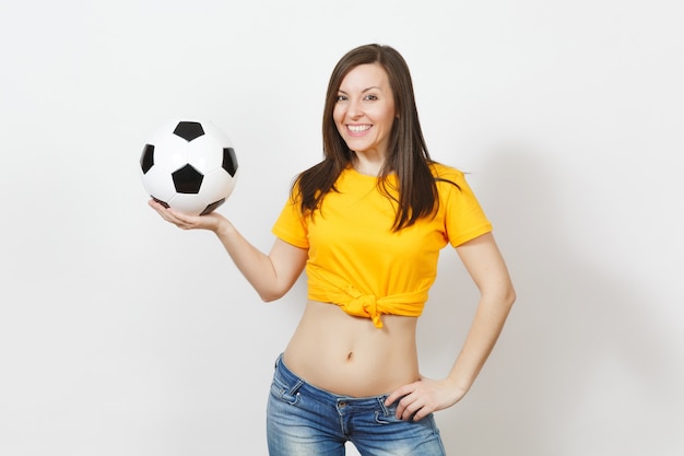 아름 다운 유럽 젊은 강한 슬림 섹시 한 여자, 축구 팬 또는 흰색 배경에 고립 된 축구 공을 들고 노란색 유니폼 선수. 스포츠, 축구, 건강, 건강한 라이프 스타일 개념을 재생합니다.