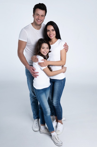 Beautiful excited and the funny family team is posing in a white t-shirt while they isolated on white background in studio.