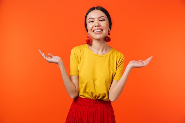 Beautiful excited happy young woman posing isolated over orange wall showing copyspace