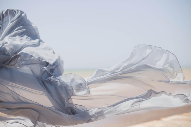 Foto bellissimo tessuto in raso di tulle al vento, il movimento su deserto, mare, natura, estate
