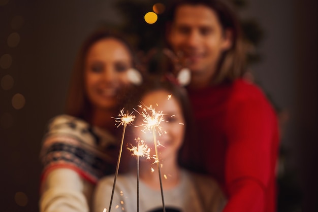 Beautiful family celebrating Christmas and holding sparklers