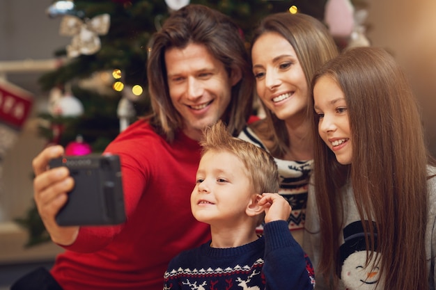 Bella famiglia che festeggia il natale a casa e scatta foto istantanee