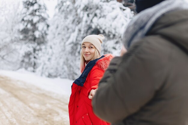 A beautiful family couple walking on a snowy road in the woods