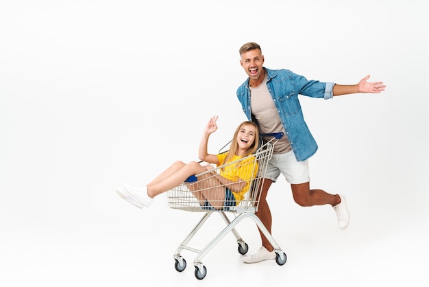 beautiful family father and daughter having fun while having ride in shopping cart isolated on white