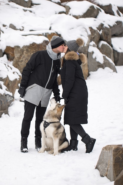 美しい家族、犬と冬の森の男と女。犬のシベリアンハスキーと遊ぶ。