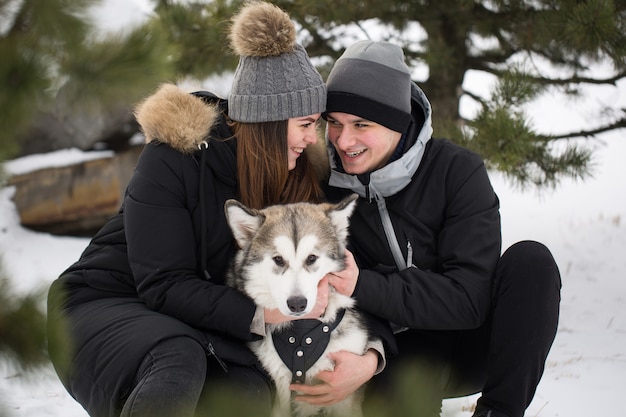아름 다운 가족, 남자와 강아지와 함께 겨울 숲에서 여자. 개 시베리안 허스키와 함께 플레이.