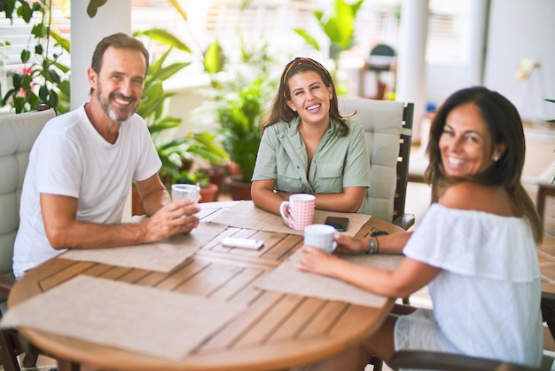 Beautiful family sitting on terrace drinking cup of coffee speaking and smiling