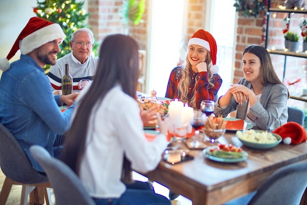 Beautiful family wearing santa claus hat meeting smiling happy and confident. Eating roasted turkey celebrating Christmas at home