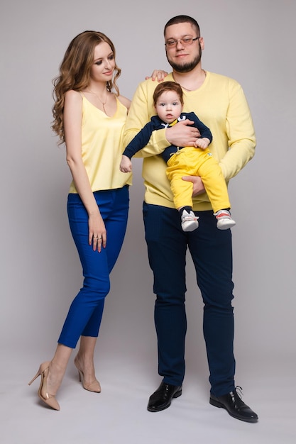 A beautiful family with a small child in the studio on a gray background