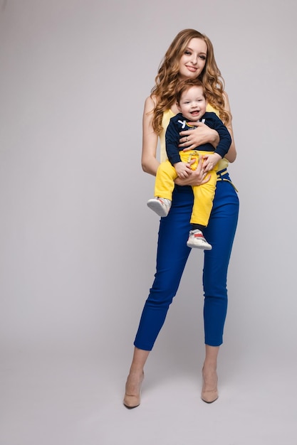 Photo a beautiful family with a small child in the studio on a gray background