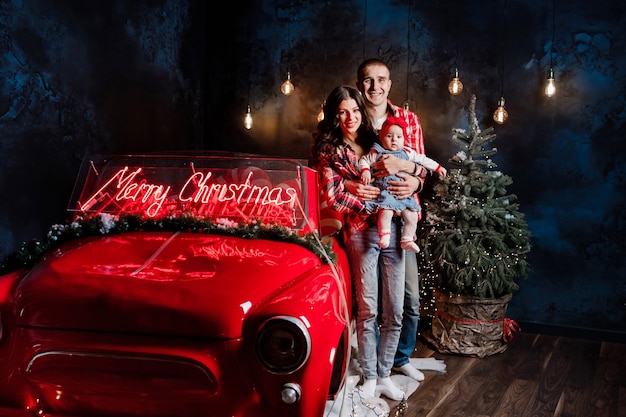 Beautiful family with their baby next to a retro car