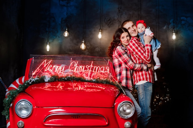 Beautiful family with their baby next to a retro car