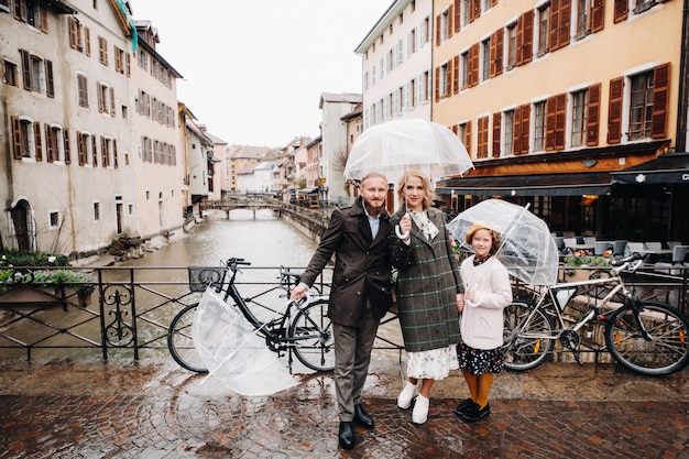 Beautiful family with umbrellas in rainy weather in Annecy