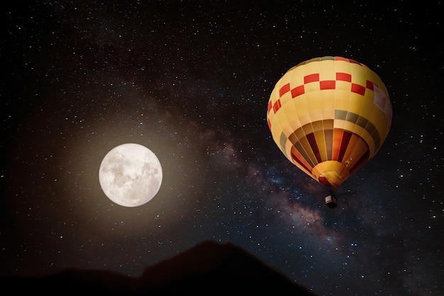 Beautiful fantasy of hot air balloon and full moon with milky way star in night skies background. Retro style artwork with vintage color tone