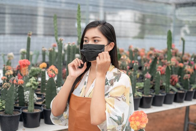 Beautiful farmer checking quality of cactus plants with tablet on the pot at cactus farm house.