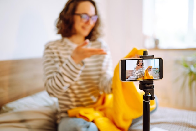 Beautiful fashion blogger holding yellow sweater dreamily recording video for vlog Online marketing