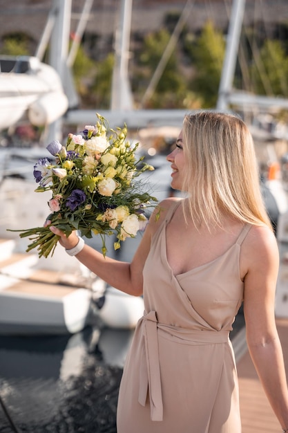 A beautiful fashion caucasian woman with flowers on luxury yachts background in marina