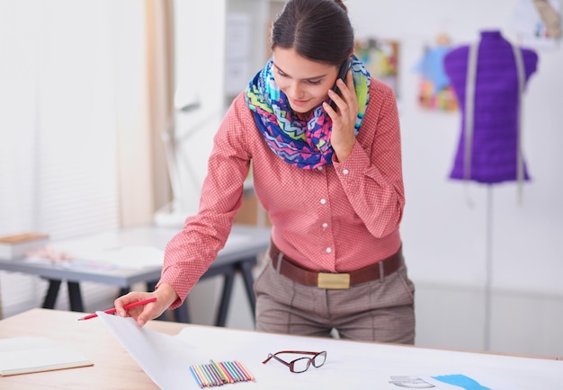 Beautiful fashion designer sitting at the desk in studio