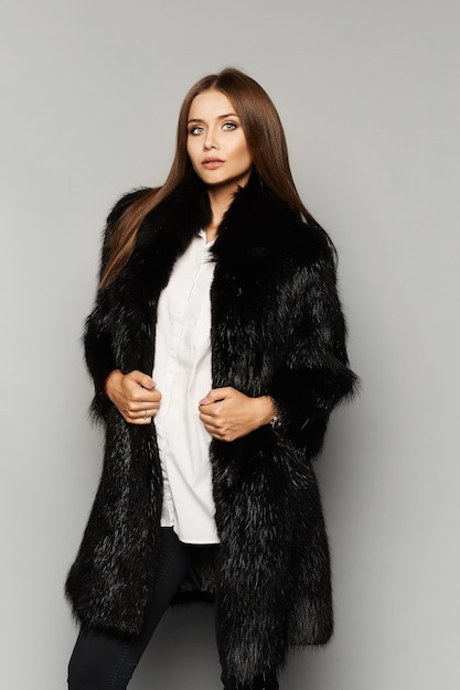 Beautiful fashion model girl with perfect makeup in luxury fur coat, isolated on the background.