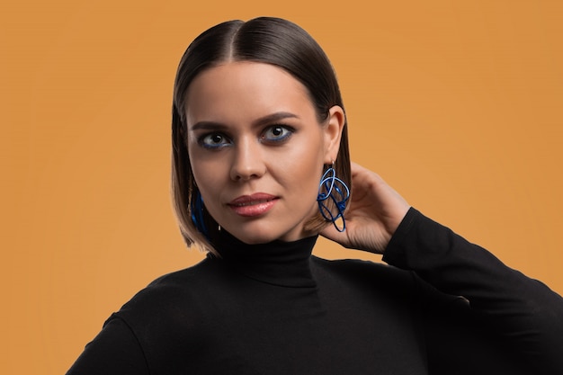 Beautiful fashion model with smokey makeup and big eyes showing blue earrings