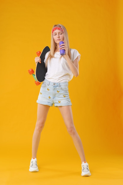 Beautiful and fashion teenager posing with a skateboard in studio