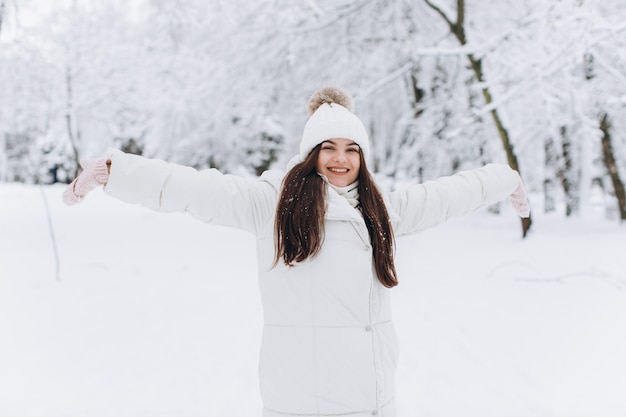 A beautiful and fashion woman in white warm clothing walking in snowy weather.