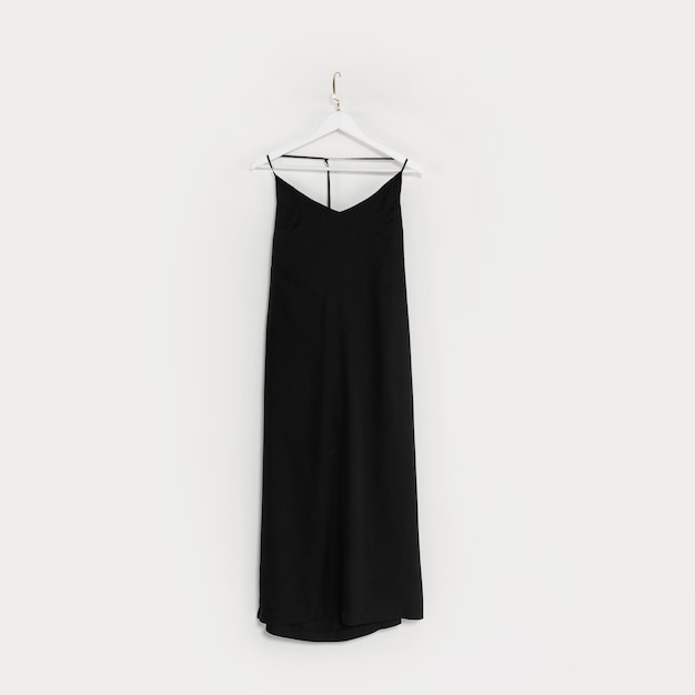 Beautiful fashionable black dress hangs on a white hanger on a white wall Women's fashion and party