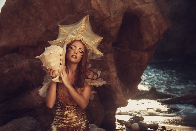 Photo beautiful fashionable mermaid sitting on a rock by the sea