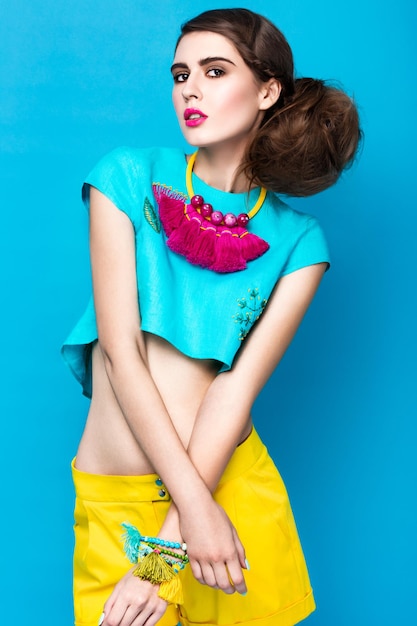 Beautiful fashionable woman an unusual hairstyle in bright clothes and colorful accessories
