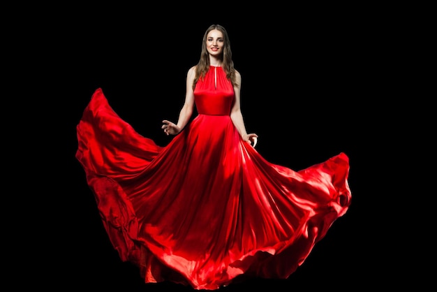 Beautiful fashionable woman wearing red silky dress isolated on black background