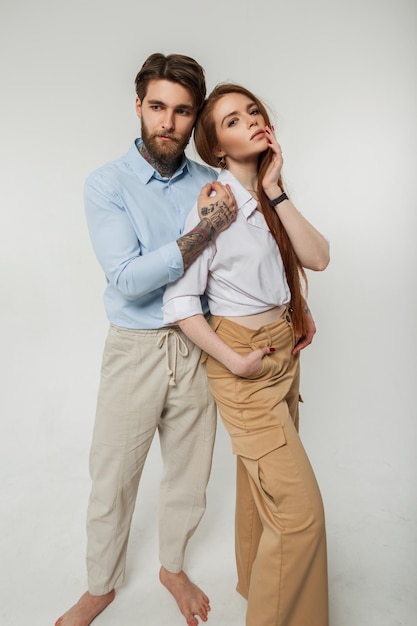 Beautiful fashionable young couple in the studio Stylish cute beauty redhead girl and brutal hipster handsome man in shirt on white background