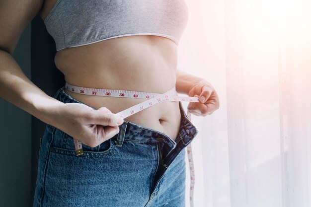 Premium Photo  Beautiful fat woman with tape measure she uses her hand to  squeeze the excess fat that is isolated on a white background she wants to  lose weight the concept