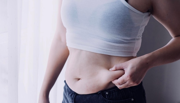 Beautiful fat woman with tape measure She uses her hand to squeeze the excess fat that is isolated on a white background She wants to lose weight the concept of surgery and break down fat under the