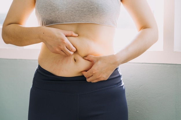 Beautiful fat woman with tape measure She uses her hand to squeeze the excess fat that is isolated on a white background She wants to lose weight the concept of surgery and break down fat under the