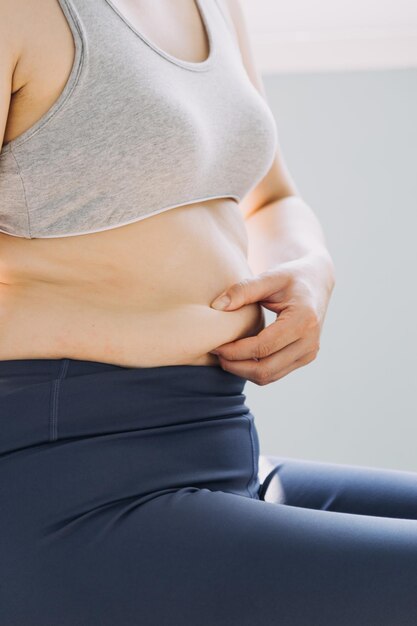 Beautiful fat woman with tape measure She uses her hand to squeeze the excess fat that is isolated on a white background She wants to lose weight the concept of surgery and break down fat under the