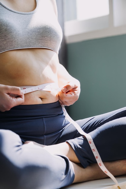 Beautiful fat woman with tape measure She uses her hand to squeeze the excess fat that is isolated on a white background She wants to lose weight the concept of surgery and break down fat under the