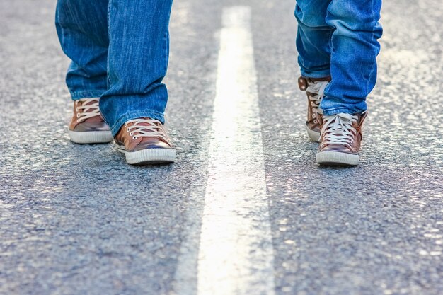 自然旅行の公園の道路上の親と子の美しい足