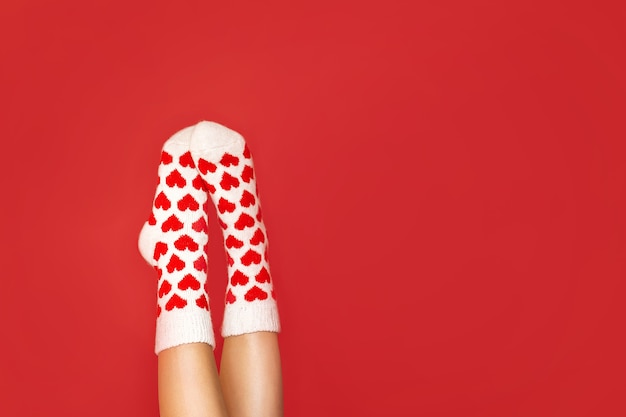 Beautiful feet in warm socks with a hearts print on a red