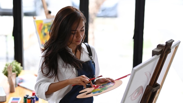 Beautiful female artist painting with watercolor in art workshop