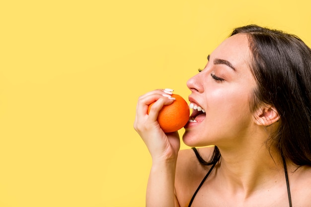 Beautiful female biting citrus fruit