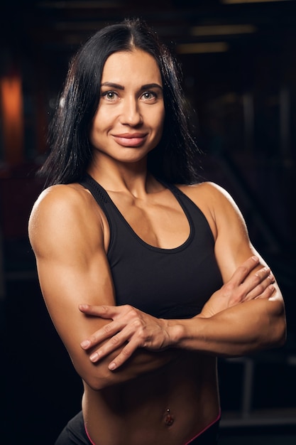 Beautiful female bodybuilder wearing sport clothes and standing with her arms crossed while looking at the camera