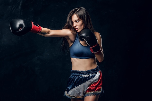 Beautiful female boxer is demonstrating her tactic attack while posing for photographer.