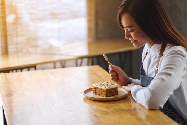 A beautiful female chef baking and eating a piece of homemade carrot cake in wooden tray