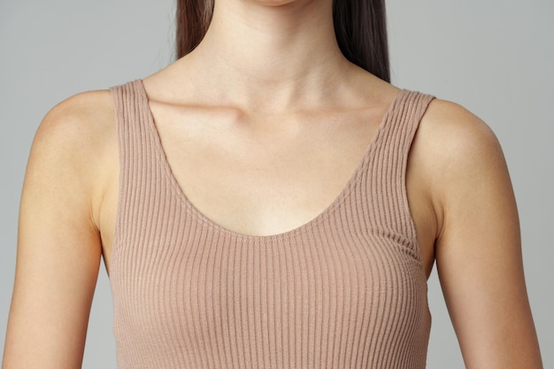 Beautiful female collarbone in cotton beige underwear over grey studio background