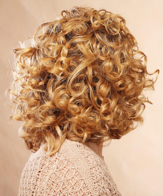 美しい女性の巻き毛のブロンドの髪の背面図