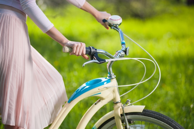 Beautiful female cyclist with retro bicycle in the spring garden