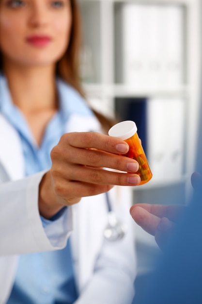 Beautiful female doctor hold in arms pill bottle