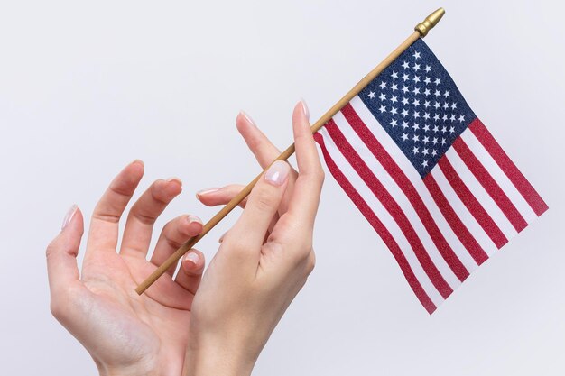 A beautiful female hand holds an American flag on a white background