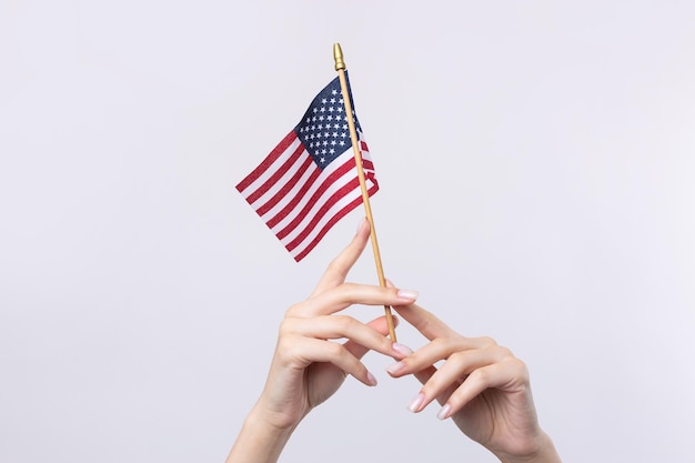 아름다운 여성의 손은 흰색 바탕에 미국 국기를 들고 있다