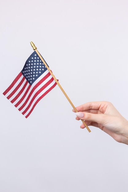 Photo a beautiful female hand holds an american flag on a white background